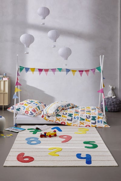 Helles Kinderzimmer mit weißem Hausbett, Bettwäsche mit Alphabet-Muster, einem Teppich mit bunten Zahlen und Heißluftballon-Lampions.