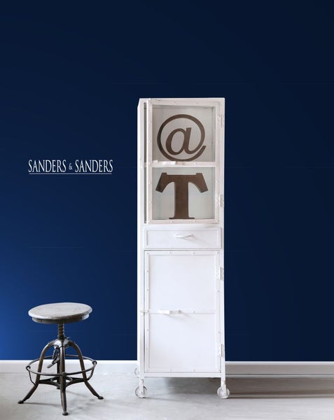 Szene mit weißem Schrank auf Rollen, Barhocker und dekorativen Symbolen