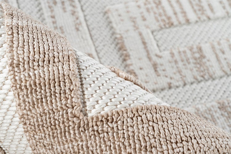 Nahaufnahme eines beige-cremefarbenen Teppichs mit gewebter Textur und geometrischem Muster.