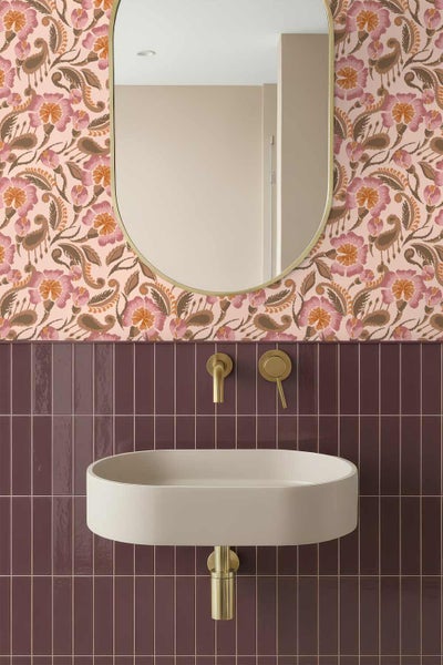 Modernes Badezimmer mit ovalem Waschbecken, goldfarbener Wandarmatur, dunkelroten vertikalen Fliesen und floraler Tapete.