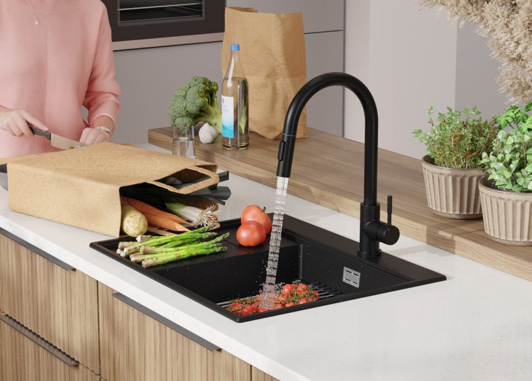 Schwarze Küchenarmatur mit Gemüse in einer Küchenspüle.