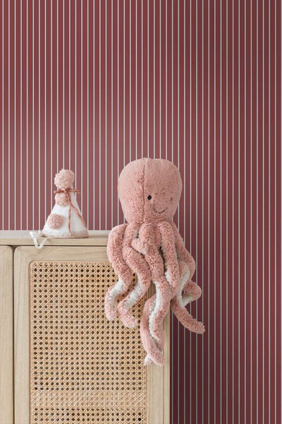 Vliestapete mit Streifenmuster vor einem Holzschrank mit Rattangeflecht und einem Plüsch Oktopus.