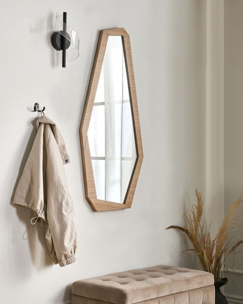 Szene mit Wandspiegel, Wandleuchte, Hocker, Jacke an Haken und Dekoration