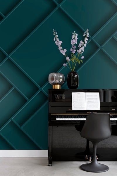 Einrichtungsszene mit schwarzem Klavier, Stuhl, Tischlampe und Blumenvasen vor einer Wand mit Zierleisten