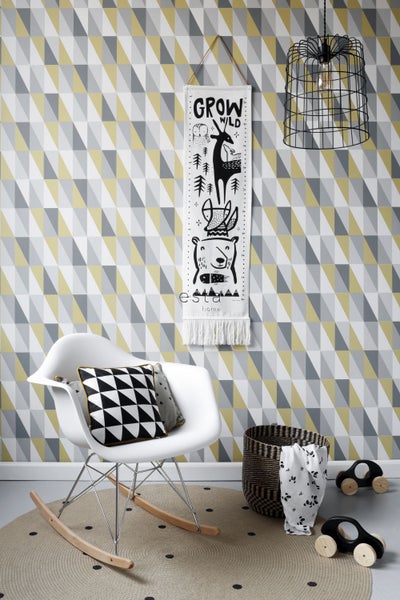 Einrichtungsidee für ein Kinderzimmer mit geometrischer Tapete, Wachstumsmesser, Schaukelstuhl, Teppich und Dekoration