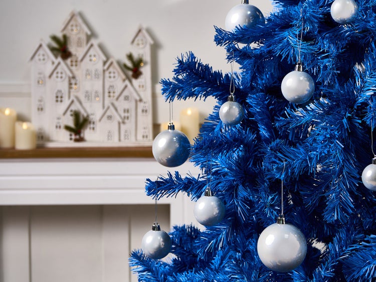 Blauer Weihnachtsbaum mit silberfarbenen Kugeln und Häuserdekoration