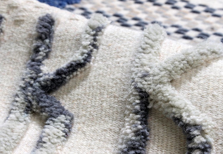 Nahaufnahme eines gewebten Teppichs mit Hoch-Tief-Struktur und zotteligen geometrischen Mustern.