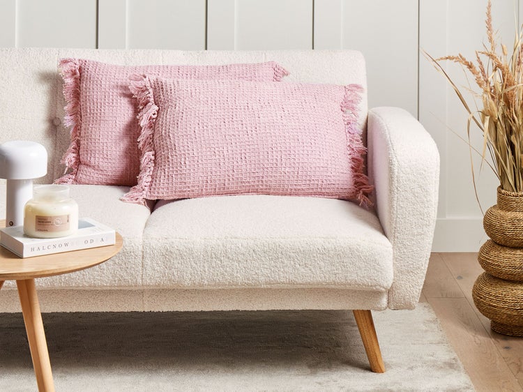 Zwei rosa Zierkissen mit Fransen auf einem Sofa