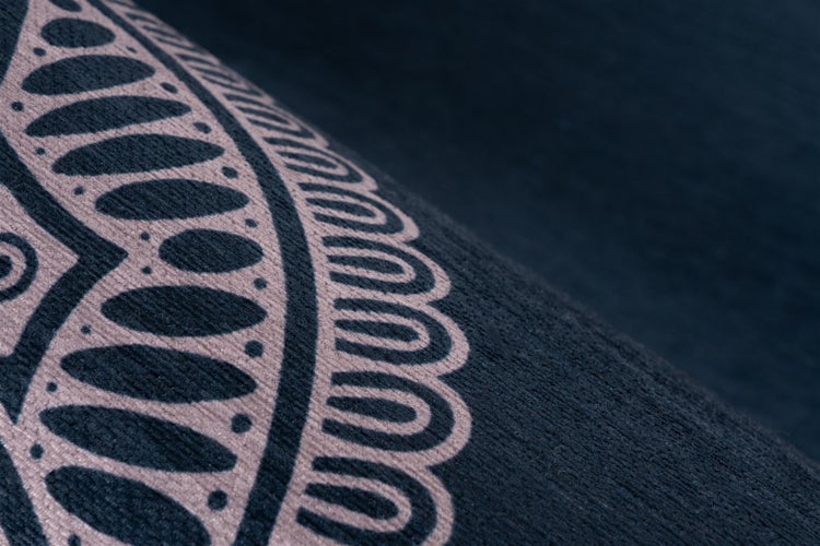 Nahaufnahme eines Teppichs mit ornamentalem Muster und weicher, strukturierter Oberfläche.