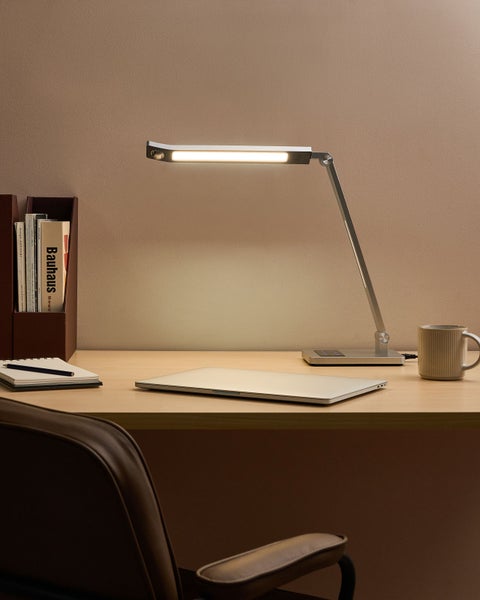 Schreibtisch mit Schreibtischlampe, Laptop, Notizblock und Tasse für eine organisierte Arbeitsatmosphäre