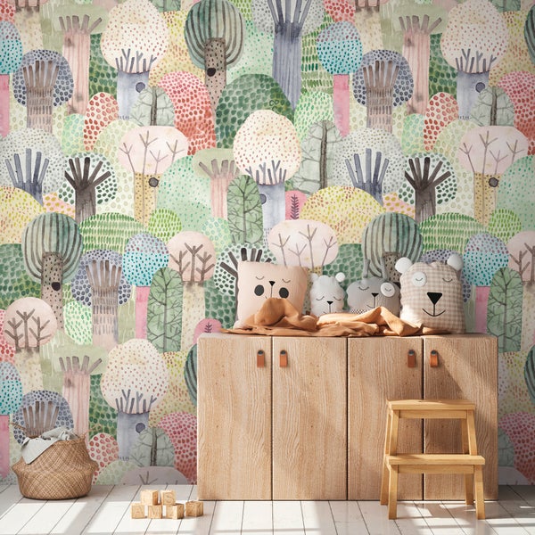Helles Kinderzimmer mit bunter Wald-Mustertapete in Aquarell-Optik, einem Sideboard aus Holz sowie Tierkissen und einem Tritthocker.