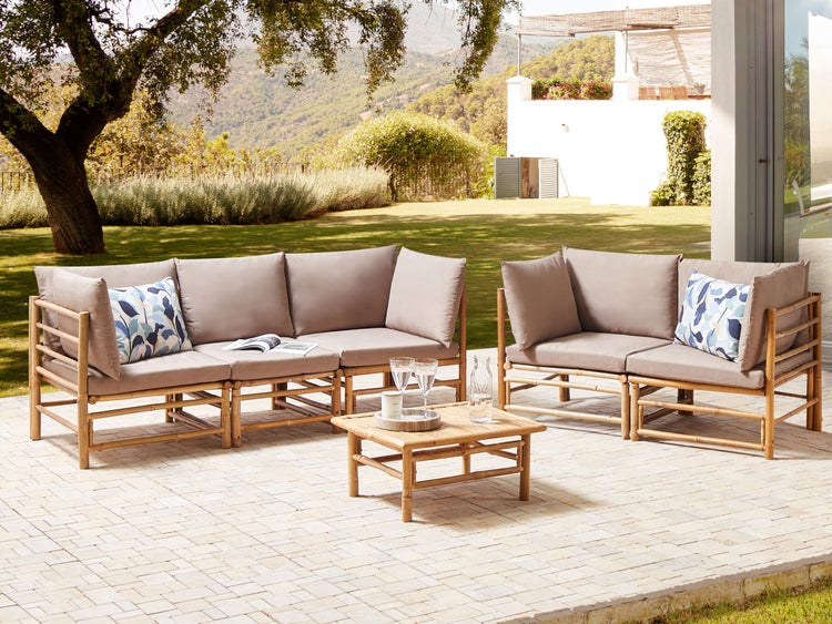 Gartenlounge-Set aus Bambus mit hellen Polstern und Dekokissen auf einer Terrasse