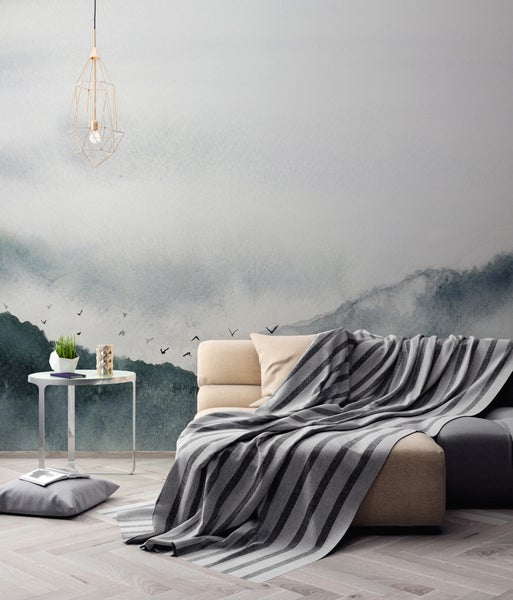 Modernes Wohnzimmer mit einer Fototapete im Aquarellstil mit Bergmotiv, einem Sofa mit gestreifter Decke und einer Metall-Pendelleuchte.