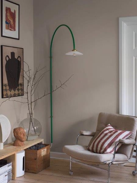 Schlafzimmer mit gestreifter Tapete, Holzbett, Nachttisch, Lampe und Zimmerpflanzen.