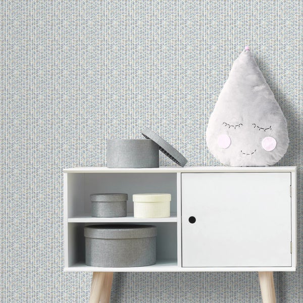 Tapete mit feinem geometrischem Fischgrätmuster in einem hellen Kinderzimmer mit weißem Sideboard, Aufbewahrungsboxen und einem Dekokissen.