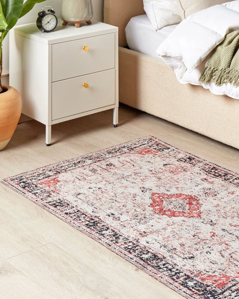 Ein Schlafzimmer mit einem gemusterten Teppich, einem Nachttisch und einem Bett.