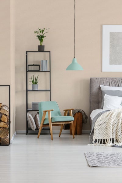 Helles Schlafzimmer mit Bett, Sessel, Regal und Dekorationen