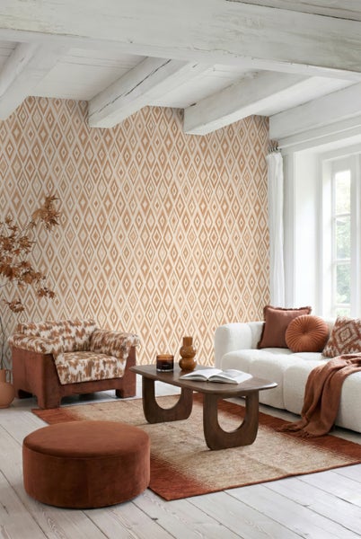 Heller Wohnraum mit geometrischer Rauten-Tapete, Holzbalken, weißem Sofa und erdfarbenen Möbeln im modernen Boho-Stil.