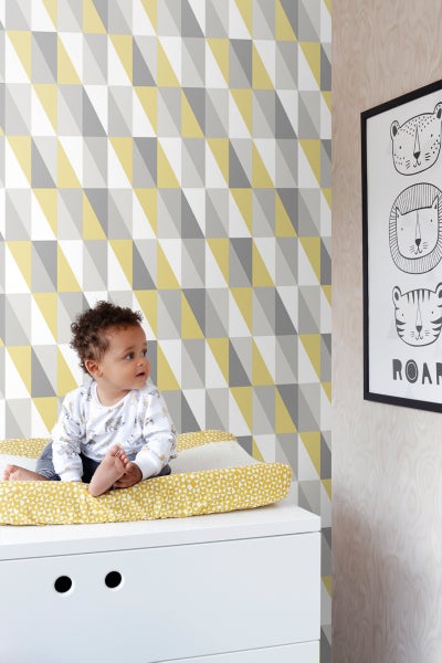 Babyzimmer mit geometrischer Tapete, Wickelauflage und Tierbild