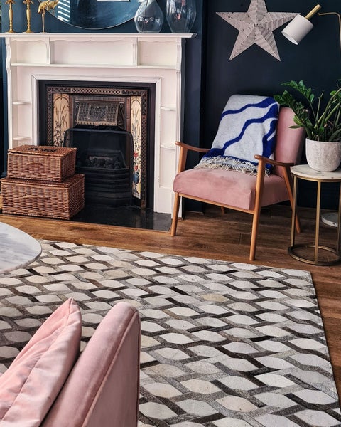 Wohnzimmer mit Kamin, Teppich, Sessel und Beistelltisch.