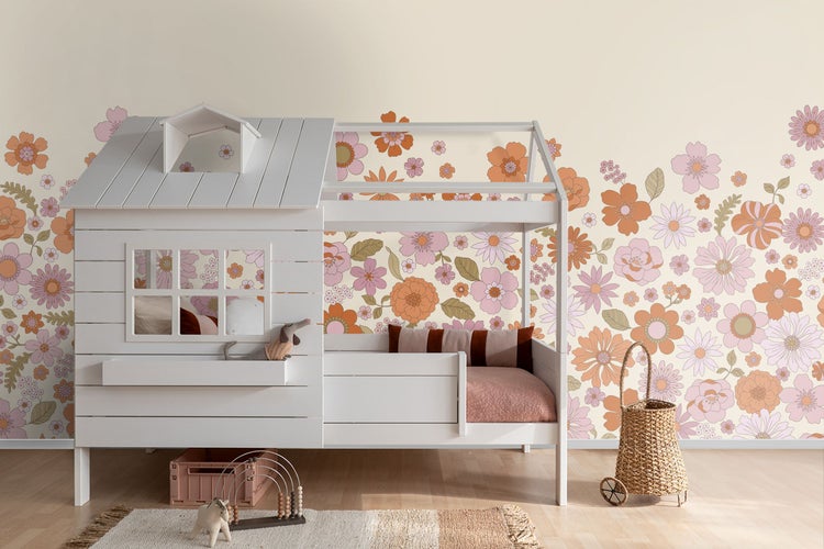 Kinderzimmer mit Hausbett, Teppich und Spielzeug vor einer geblümten Tapete
