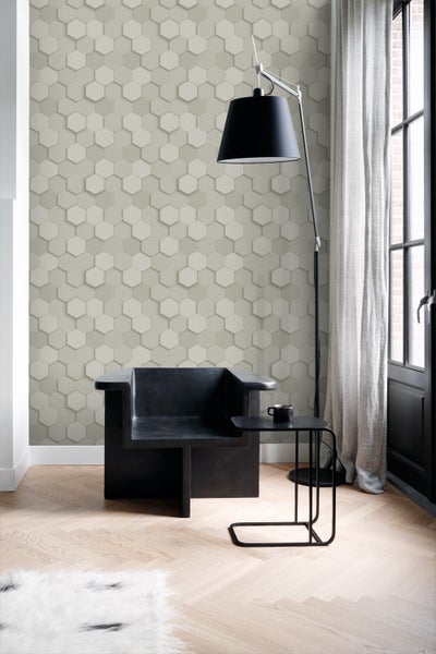Wohnraum mit dreidimensionaler Sechsecktapete, Sessel, Stehlampe und Beistelltisch.