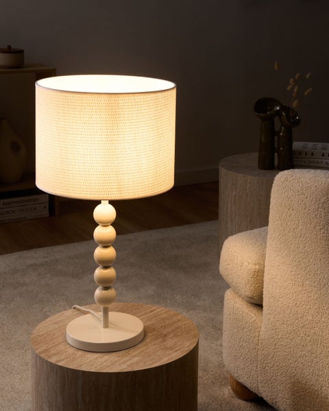 Tischleuchte mit kugelförmigem Fuß und Stoffschirm in einem modern eingerichteten Wohnzimmer.