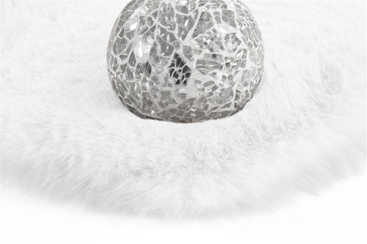 Silberne Mosaik-Glaskugel auf einem weißen Kunstfellteppich.