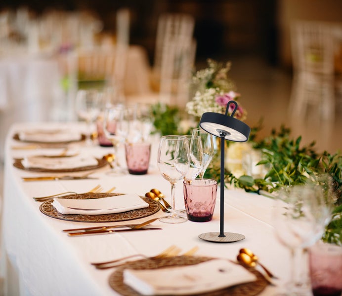 Tischdekoration mit Tischleuchte, Geschirr und Gläsern für eine festliche Tafel