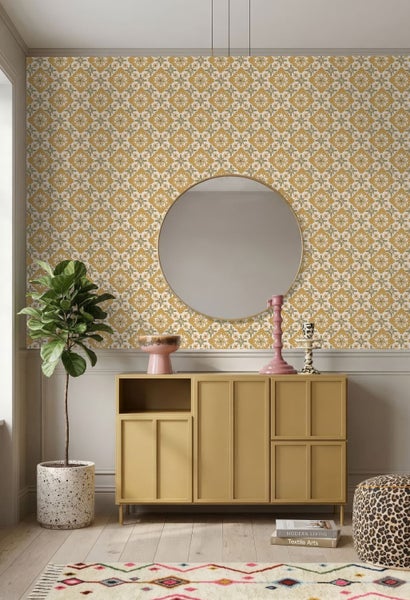 Wohnzimmer mit Tapete in gelbem Blumenmuster, gelbem Sideboard, rundem Spiegel und einer Zimmerpflanze.