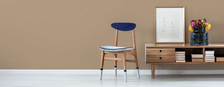 Modernes Wohnzimmer mit Holzstuhl mit blauem Samtbezug, Sideboard aus Holz mit Büchern und gerahmtem Bild.