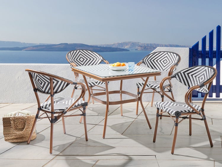 Gartenset mit Tisch und vier Stühlen mit Rattanmuster vor Meereskulisse