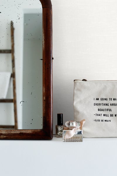 Dekorative Szene mit Spiegel, Kosmetiktasche, Nagellack und Parfüm auf einem Regal.