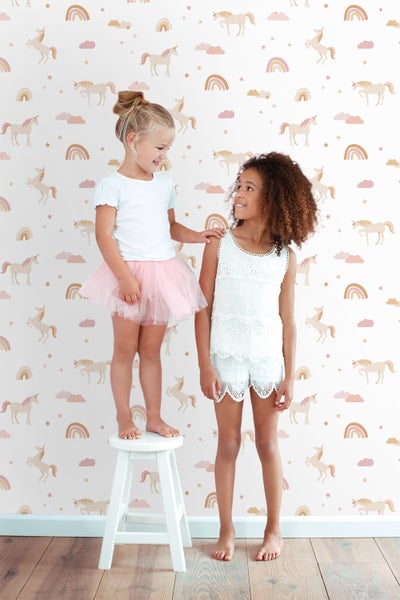 Zwei Mädchen vor einer Wand mit Einhorn- und Regenbogenmuster