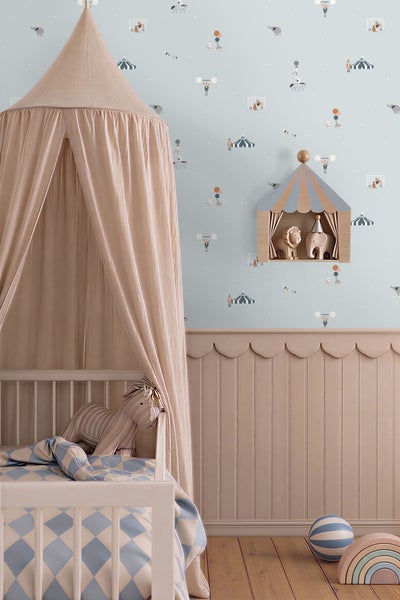 Helles Kinderzimmer mit Zirkus-Tapete, Wandpaneelen aus Holz mit Wellenkante, Babybett mit Stoff-Betthimmel und Regal in Zeltform.