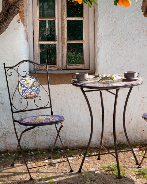 Gartenszene mit Bistrotisch und Stuhl mit Mosaikmuster