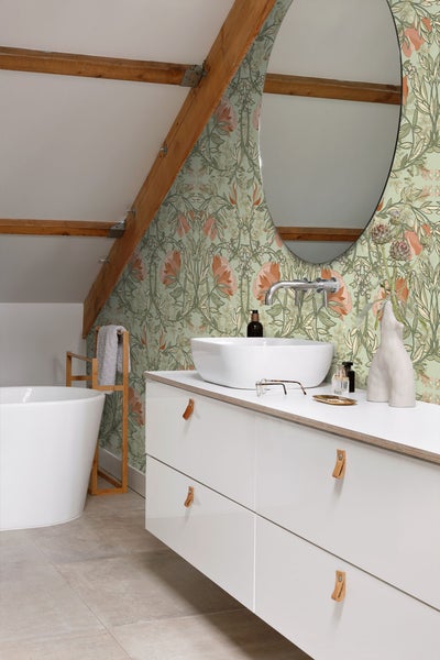 Badezimmer mit Badewanne, Waschbecken, Spiegel und floraler Tapete