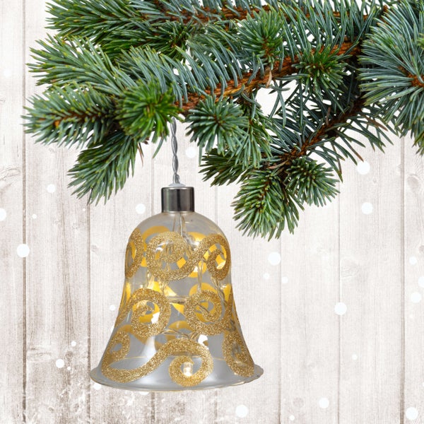 Dekoratives Weihnachtsglöckchen mit goldenen Verzierungen an einem Tannenzweig