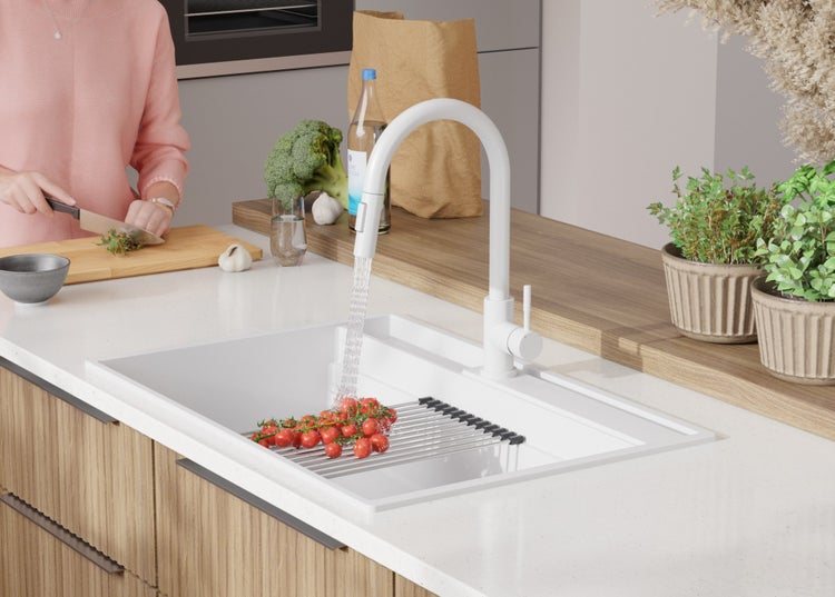 Moderne Küche mit Spüle, Armatur, Gemüse und Person bei der Zubereitung von Speisen.