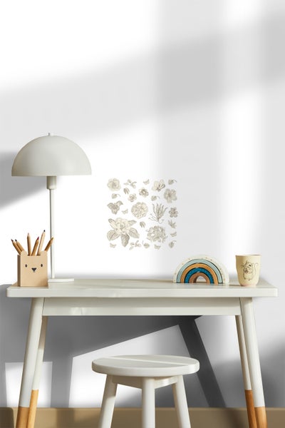 Dekoratives Kinderzimmer mit Tisch, Stuhl, Lampe, Stifthalter, Regenbogen Spielzeug, Tasse und Wandtattoo mit Blumenmotiven.