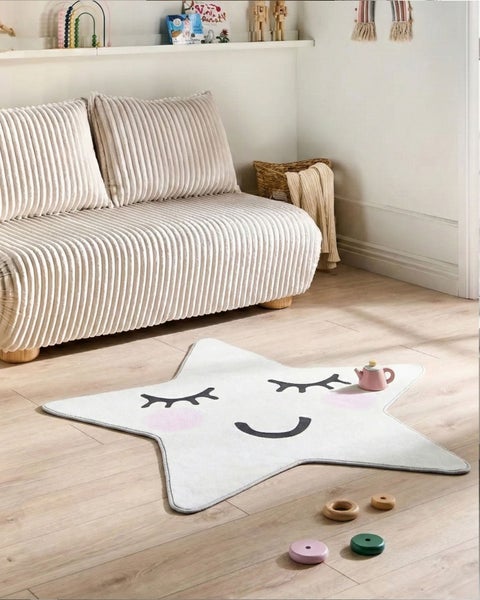 Ein Kinderzimmer mit einem Sofa und einem Teppich in Sternform mit einem Gesicht darauf.