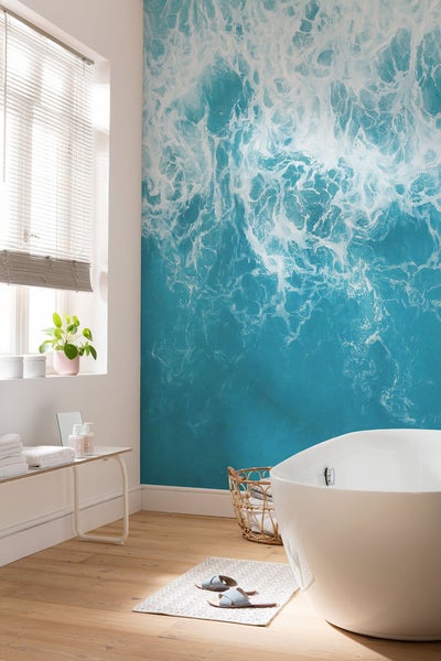 Helles Badezimmer mit Badewanne und Wandbild mit Meeresmotiv
