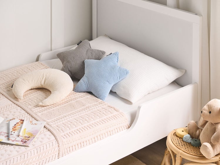 Kinderszene mit weißem Bett, Stern- und Mondkissen, Decke und Spielzeug