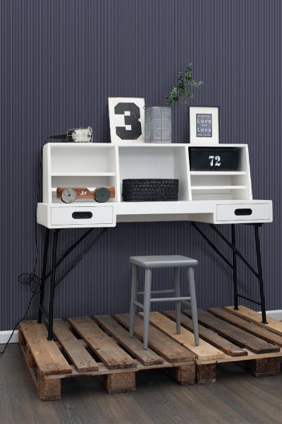 Arbeitszimmer mit weißem Schreibtisch, Regalen, Dekoration und grauem Hocker auf Holzpaletten