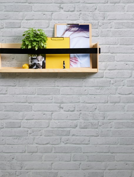 Szene mit einem Sonnenschirm, Sesseln und einem dekorativen Windlicht auf einer Holzterrasse mit einem Haus im Hintergrund.