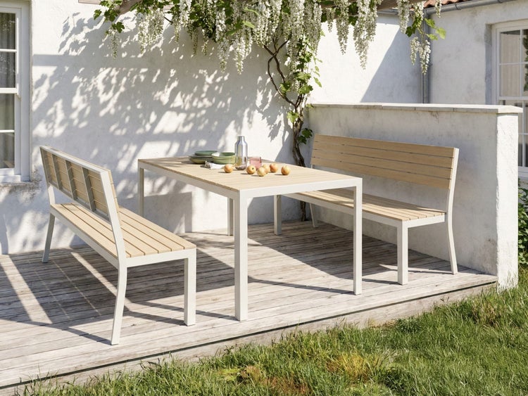 Gartenszene mit Esstisch und zwei Gartenbänken auf einer Holzterrasse