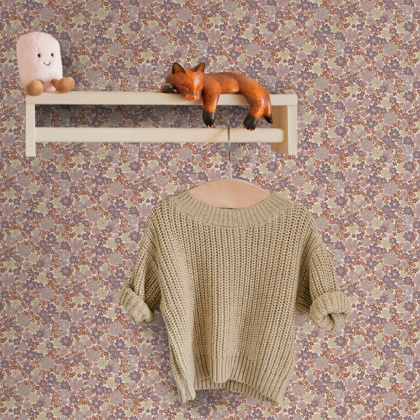 Vliestapete mit kleinteiligem Blumenmuster in einem Kinderzimmer mit Holzregal und Strickpullover.