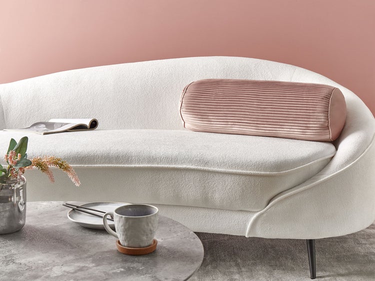 Dekorative Szene mit einem weißen Sofa, einem runden Tisch und Wohnaccessoires.