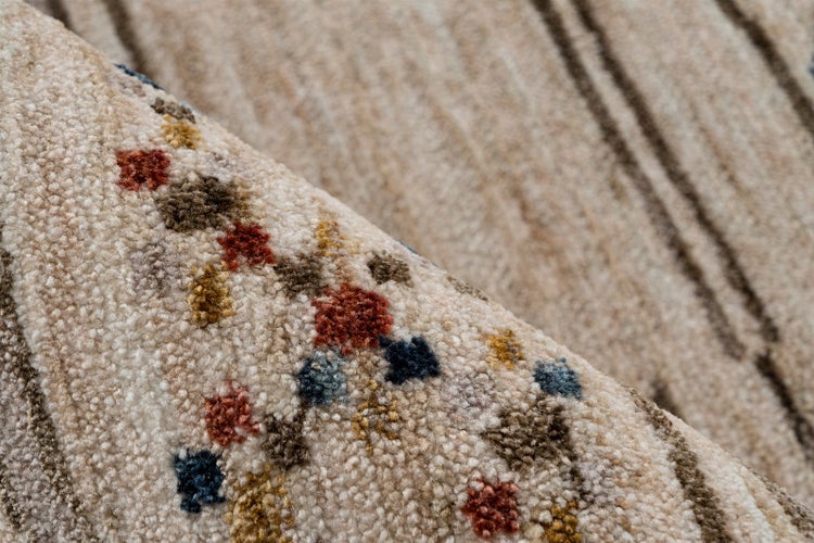 Detailaufnahme eines beigen Teppichs mit buntem Punktmuster und braunen Streifen.
