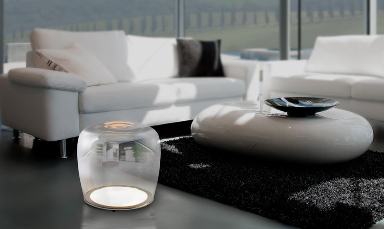 Wohnzimmer mit weißen Sofas, einem runden Tisch und einer transparenten Stehleuchte
